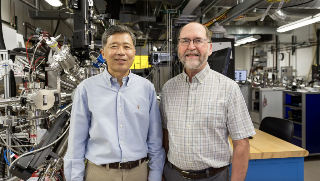 two men stand in front of lab equipment